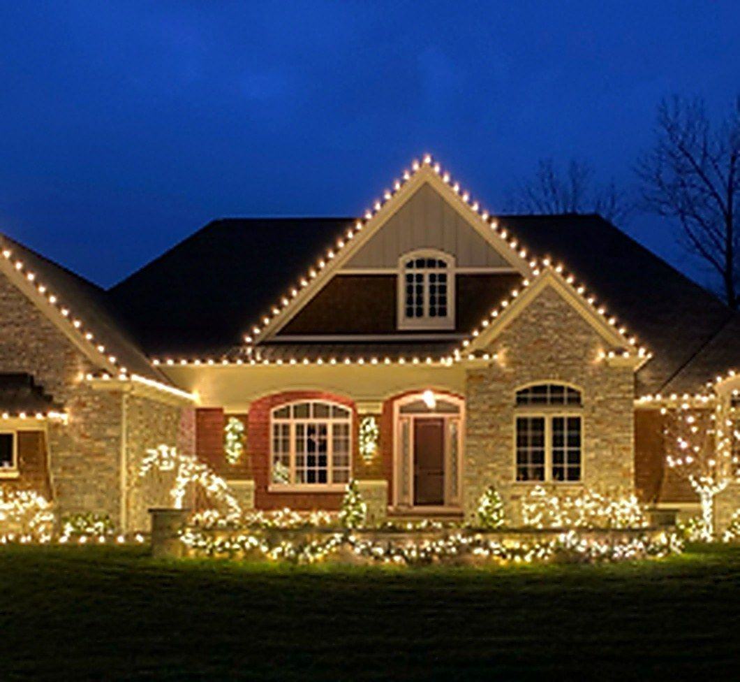 A home at night with professionally installed roofline and landscape Christmas lighting