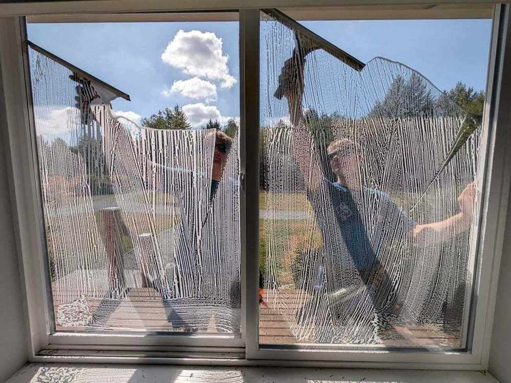 Puget Panes technicians squeegeeing soapy water off a window