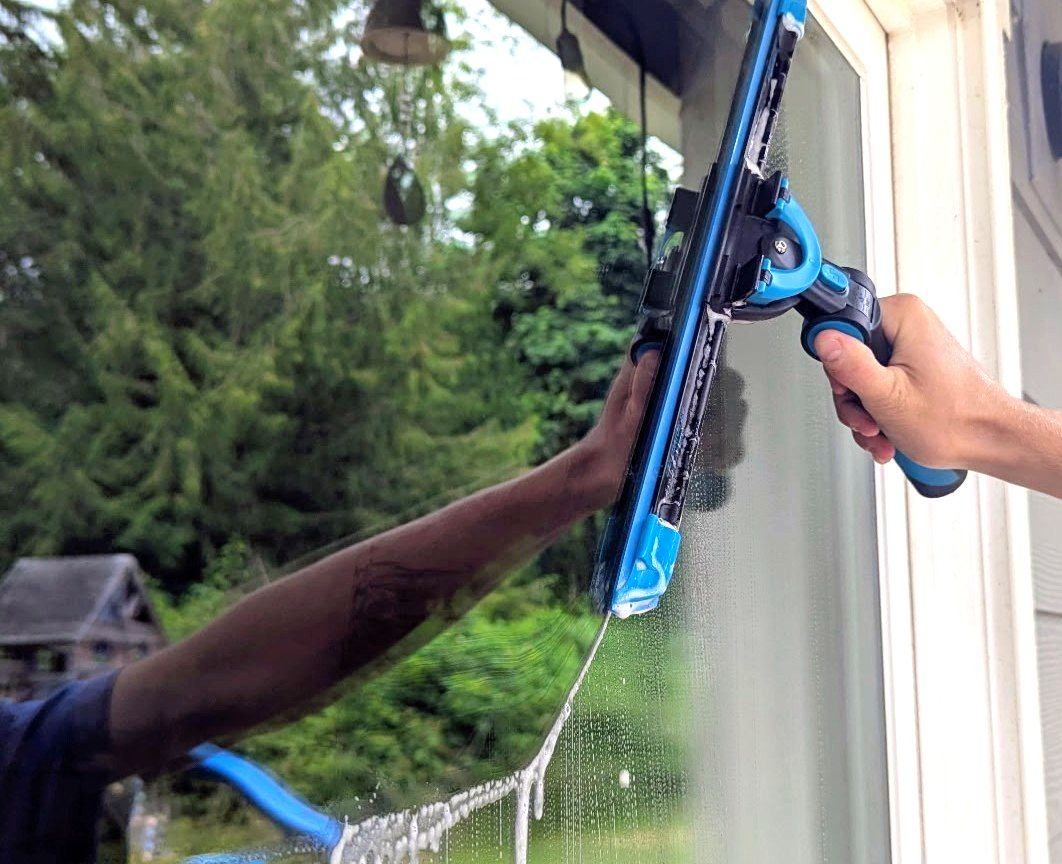Technician using a squeegee tool to clean an interior window pane