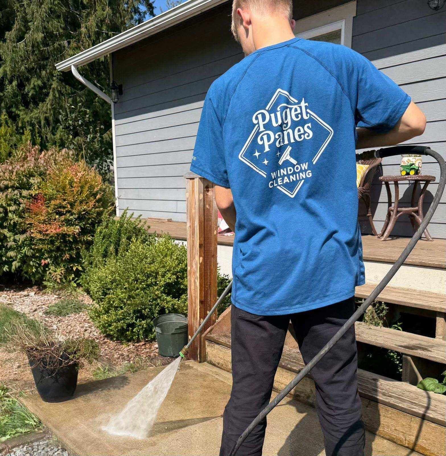 Puget Panes technician pressure washing a concrete patio