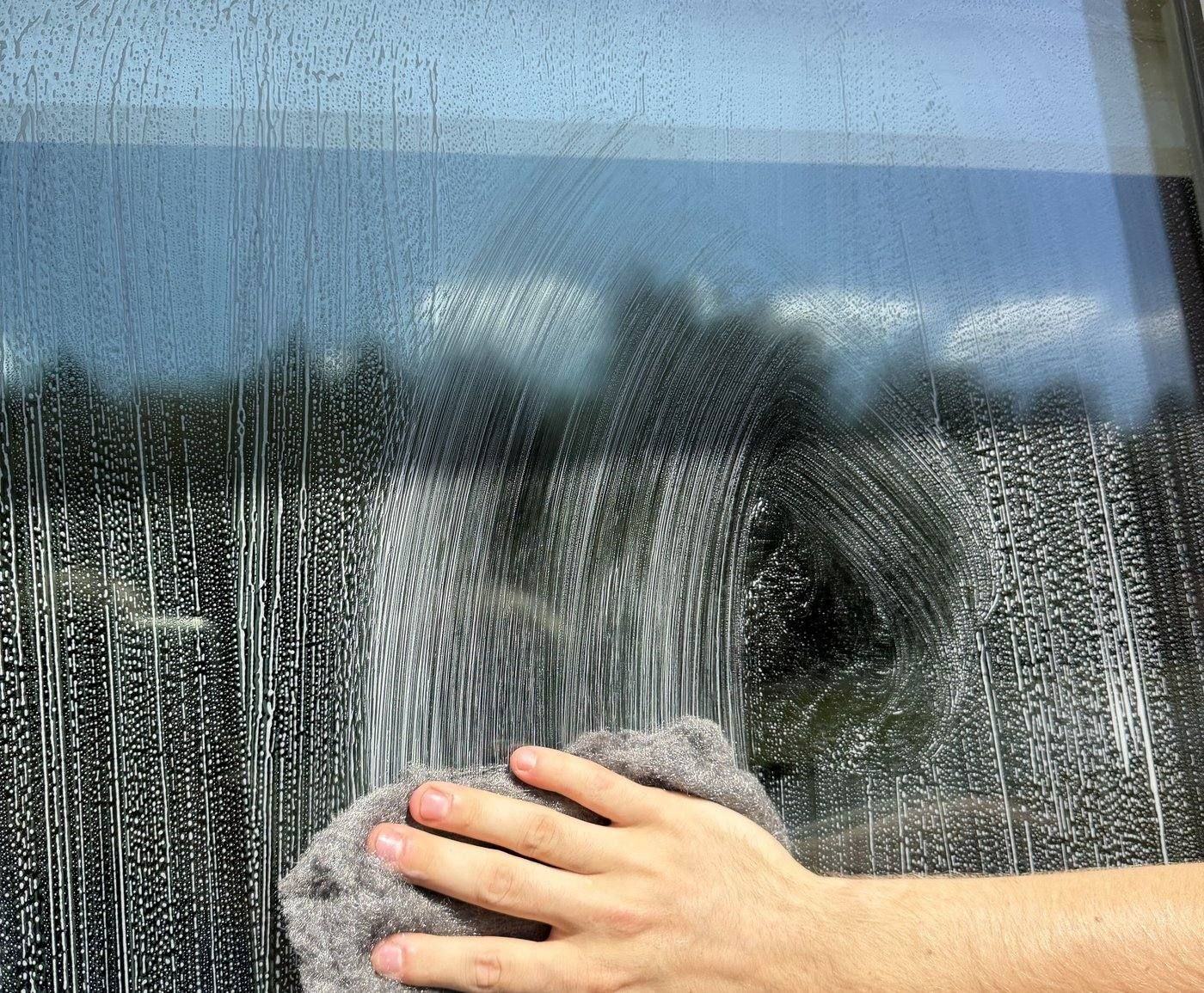 Technician wiping down window glass with a towel