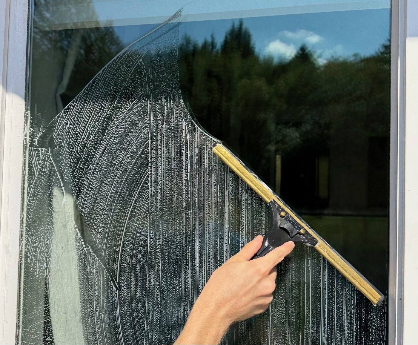 Squeegeeing soapy water off window glass